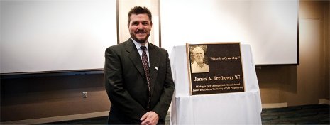 Dean Johnson standing by the memorial plaque.