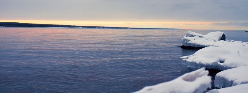 Ice-covered rocks extend out into Keweenaw Bay at sunset.