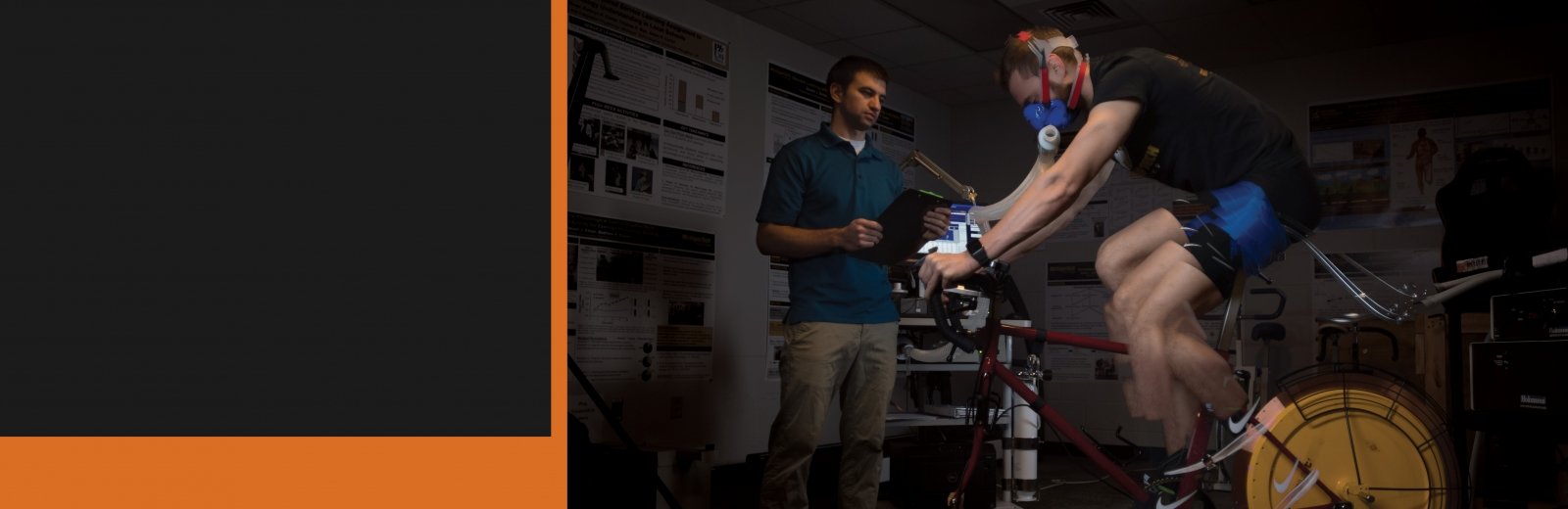 Researcher observing subject riding a stationary bike.