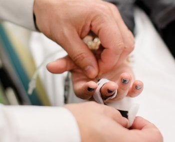 Researcher's hands strapping monitor to participant's finger.