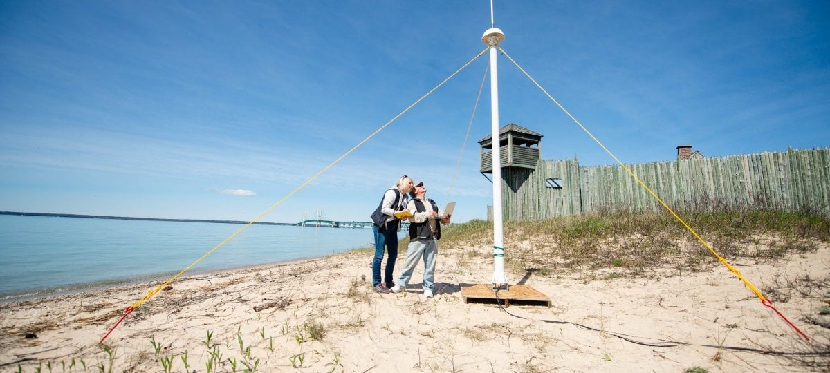 Lorelle and Guy looking up at the antenna with the water and bridge in the background.