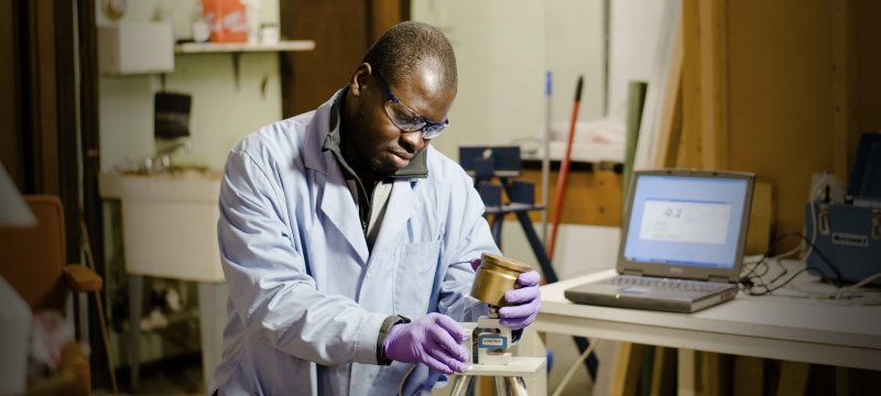 A man holds a piece of equipment to test a square of cross laminated timber