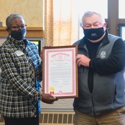 Board of Trustees member and state representative holding a framed award.