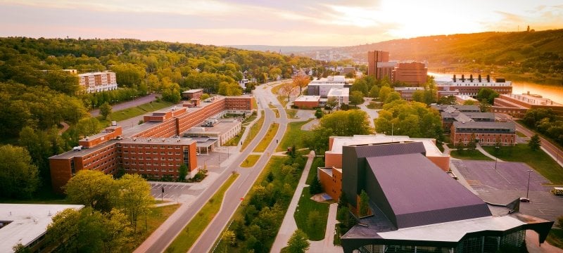 Aerial view of a bright sunset behind campus.