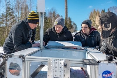 The research team looking at the rover outdoors during a field test.