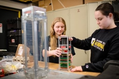 Two students workingon satellite components.