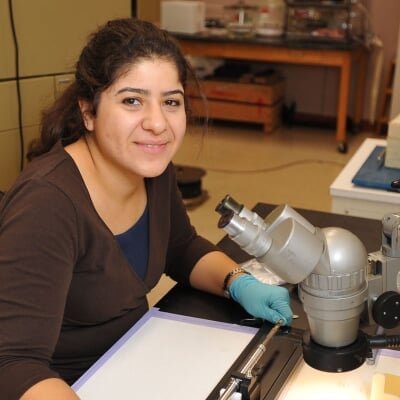 A portrait of a student using a microscope Contact Us