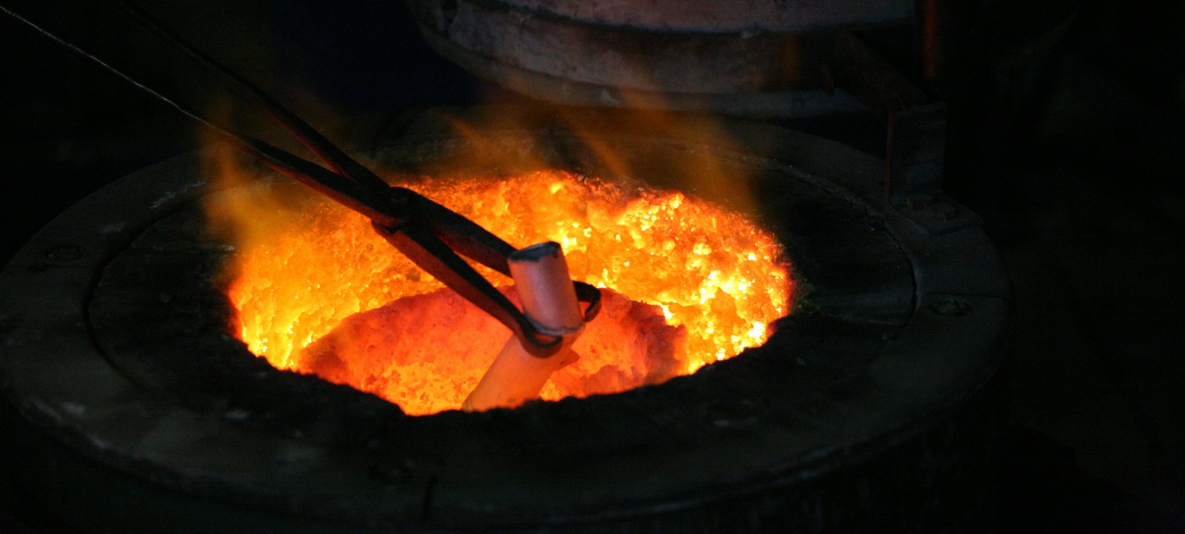 Researcher using tongs to dip a material inside the foundry.