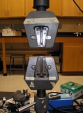 Apparatus for gripping both ends of a material and slowly pulling lengthwise.