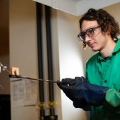 Student holding a sample with tongs.