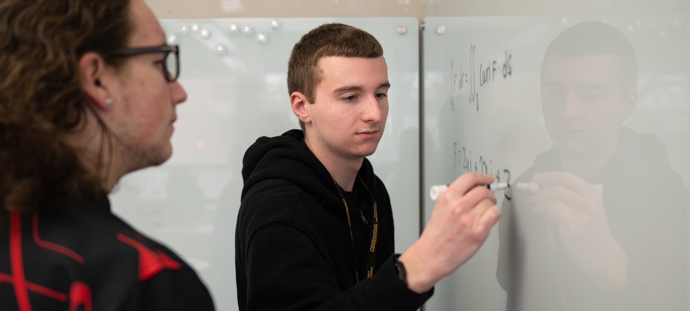 Statistics student writing on white board with faculty.