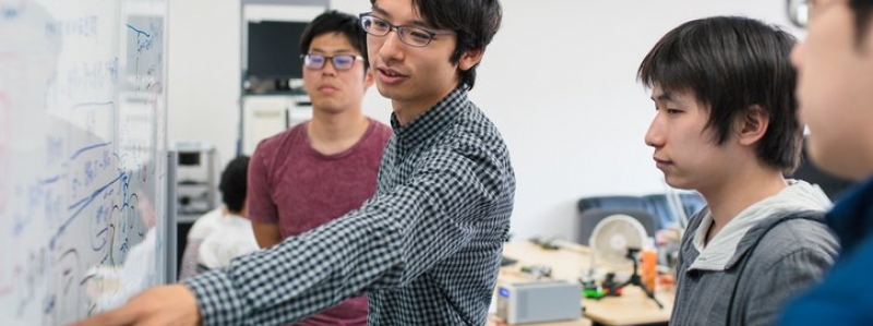 Students standing in front of a white board working on a problem