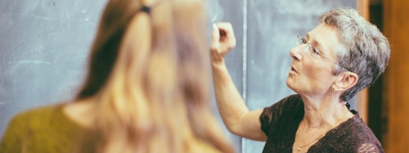 Professor working on the chalkboard with a student