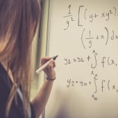 Woman writing out math equations on a whiteboard.