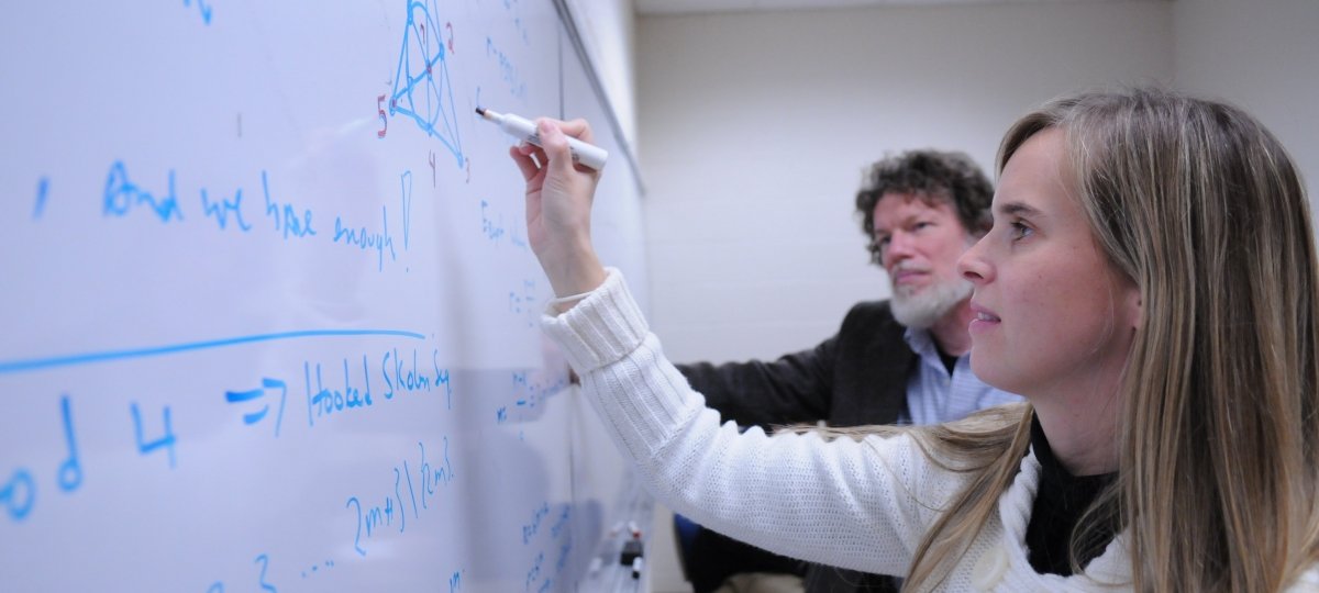 Student works on mathematical equation on a white board