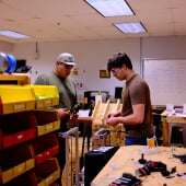 Two people gathering supplies to build a robot