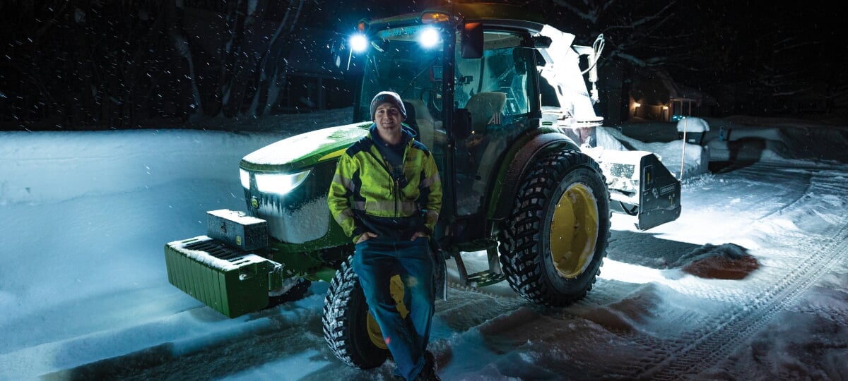 Troy Bouman standing in front of his tractor snowblower in the dark.