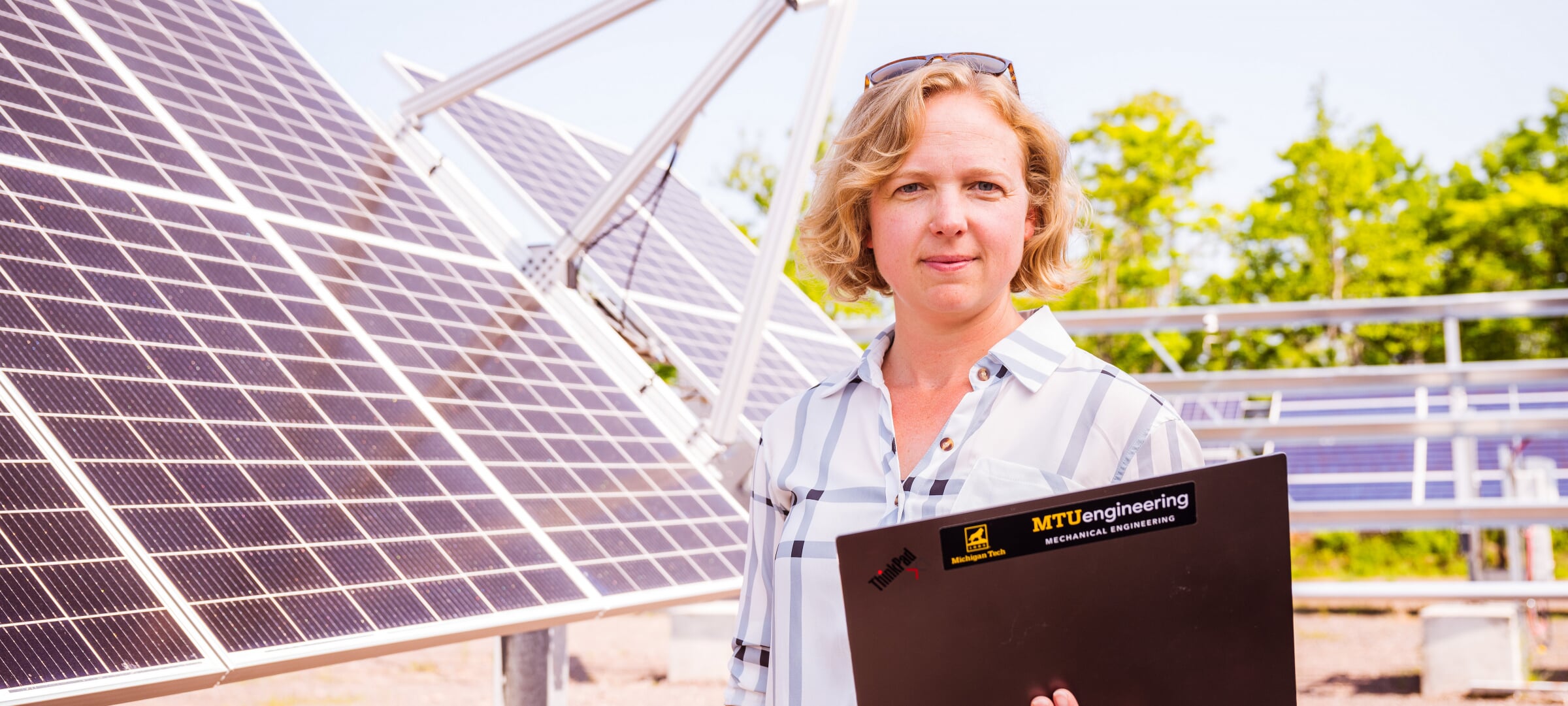 MTU Professor standing with a laptop in front of solar panels