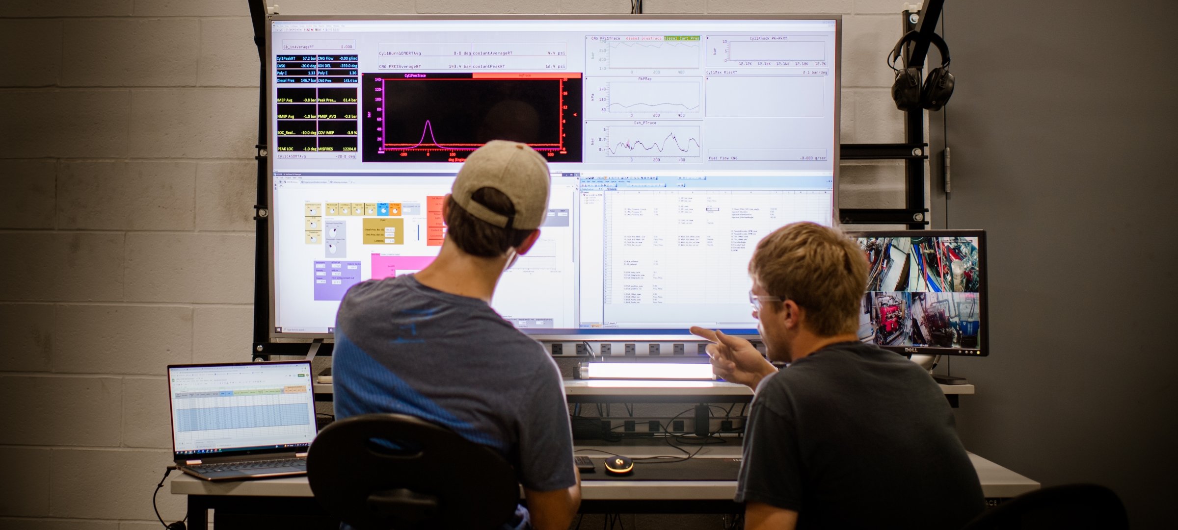 Two people looking at graph and chart results on a large screen.