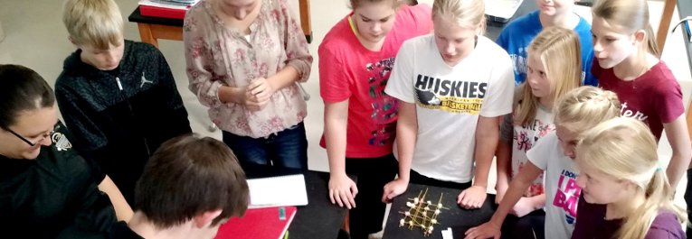 School children gather around a table for an engineering activity