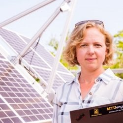 Reseasrcher standing next to solar panels.