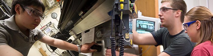 Three students adjusting settings on equipment