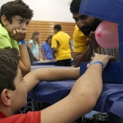 Students watching a balloon on spikes.