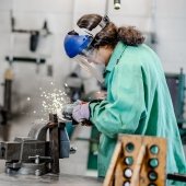 Student grining metal in a vise.