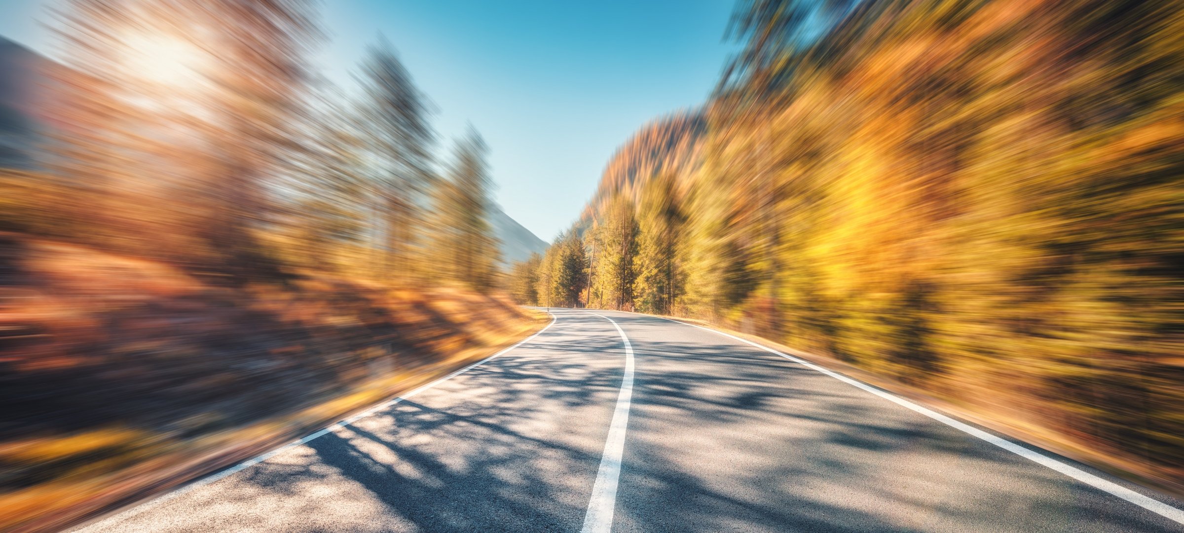 A road with blurred trees on the side.