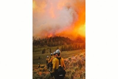 firefighters approaching a wildfire with large plume