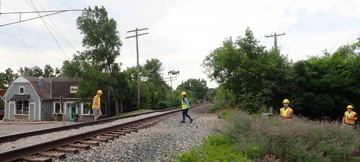 Group of people with a drone on a railroad