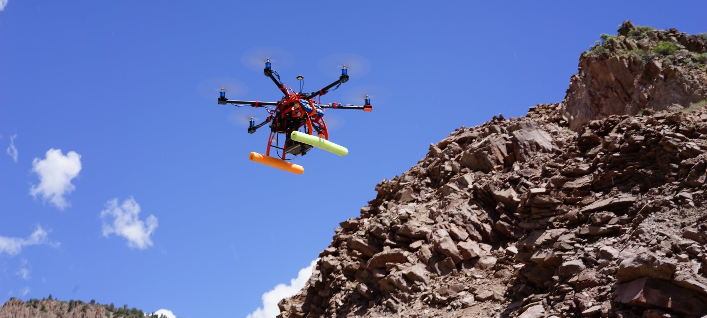 Hexacopter flying above a rocky hill.