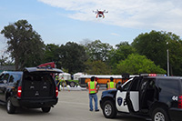 Police cars at an intersection with a drone flying overhead.