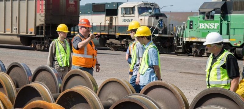 Students visiting BNSF in Superior to examine railcar wheels.