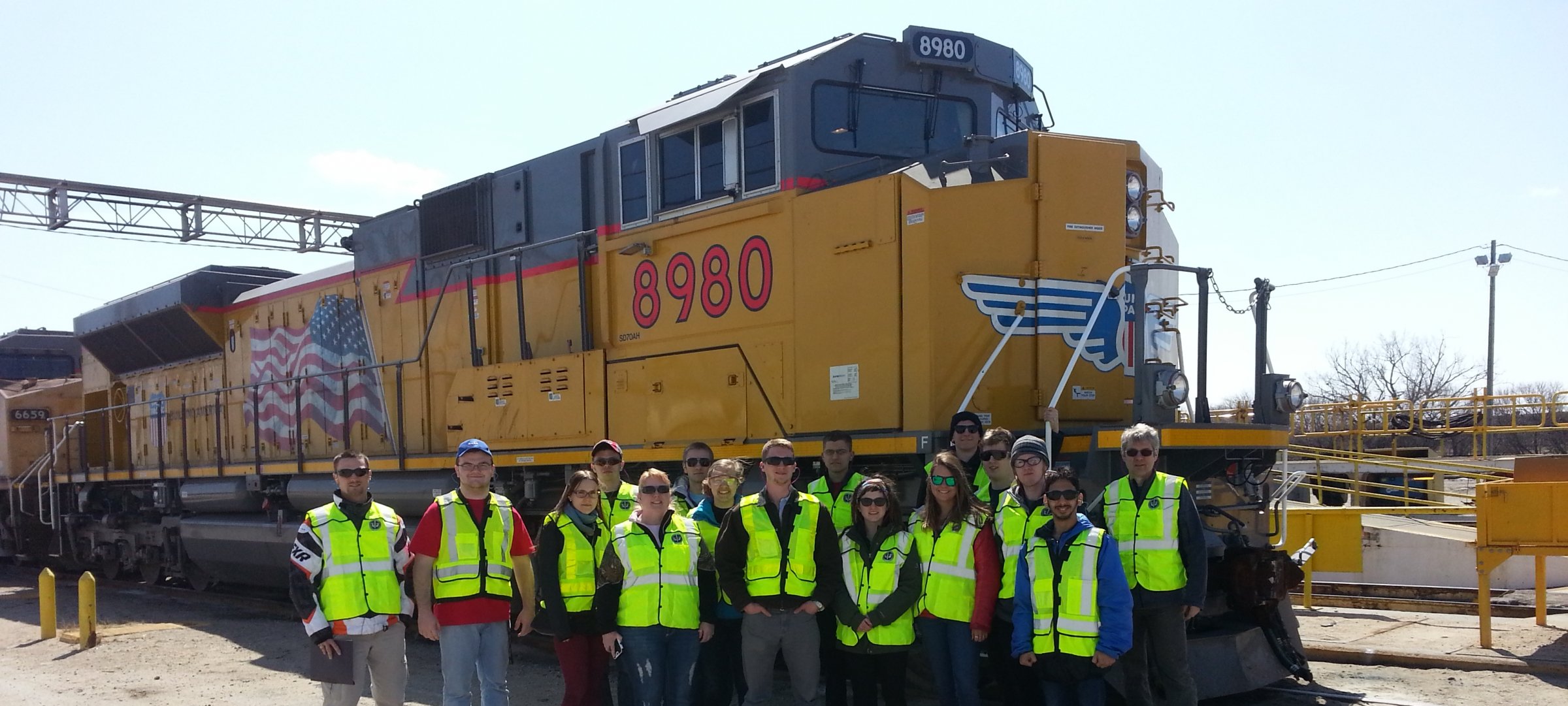 REAC students on a spring trip stand by a locomotive.