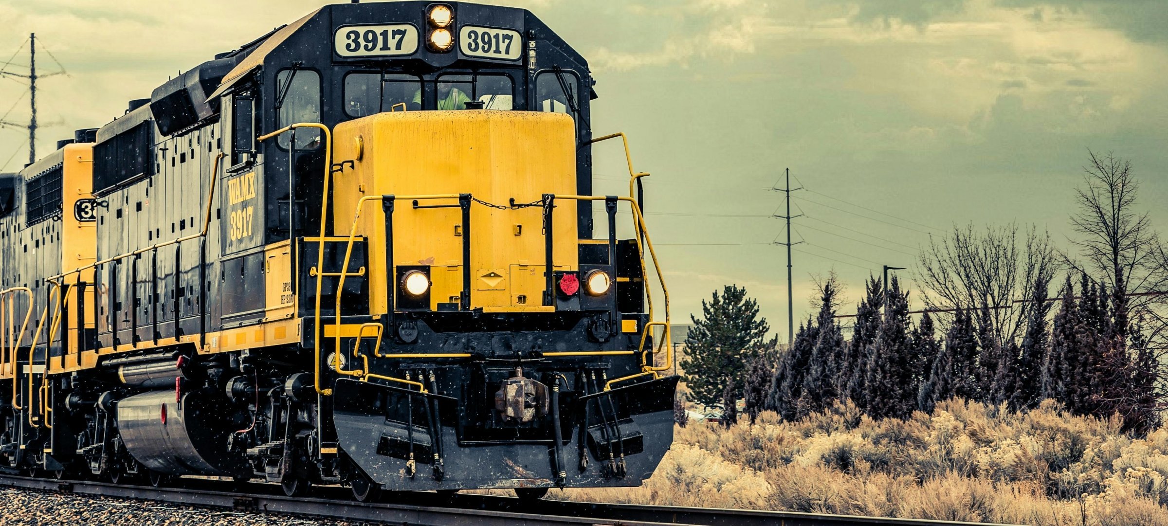 Yellow train engine travelling through the countryside.