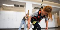 Researcher observing person in a harness falling forward.