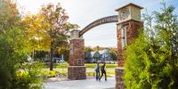 Students walking under the alumni gateway on campus.