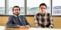 Two researchers sit at a conference table with a snow-capped hillside outdoors in the background at Michigan Technological University, where they have recently won prestigious CAREER Awards.