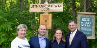 The Littmann family stands in front of a sign that says Littmann Gateway Loop