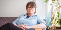 Award winner Petra Huentemeyer, a Michigan Tech physicist, in a portrait sitting on a couch on campus as she shares her work in particle astrophysics in this research profile on Michigan Tech News.