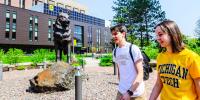 Two Michigan Tech students walk past the Husky statue on campus.