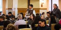 A student attending the North American Power Symposium at Michigan Tech takes part in a conversation in a ballroom setting surrounded by hundreds of other students attending the event.