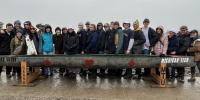 24 members of Michigan Tech Concrete Canoe Team stand behind their canoe Card Shark in a competition at a pond near Wayne State University.