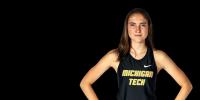 A runner in a Michigan Tech Jersey stands with hands on her hips. She just set a world record for crutch-running.