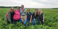 Allyson McQuiston and five co-workers laughing together in a potato field.
