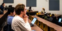 Students in a tiered seating lecture hall.