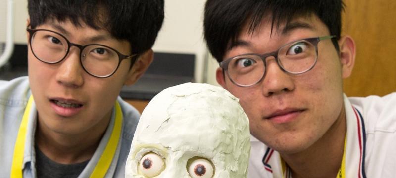 two students pose with a model skull.