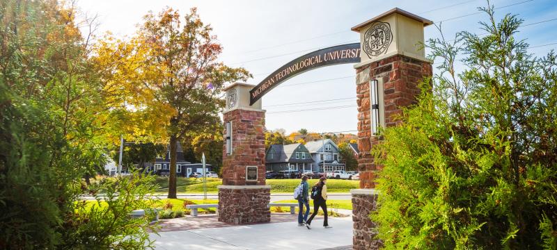 Students walking under the alumni gateway on campus.
