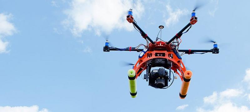 Three men controlling an airborne drone